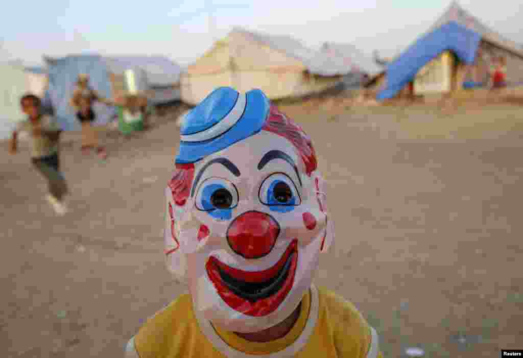Một em nhỏ người Iraq tản cư, tránh bạo lực của nhóm Nhà nước Hồi giáo ở Mosul, đeo mặt nạ chơi trong trại tị nạn Baherka ở Irbil. 