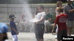 Anak-anak bermain air menyejukkan diri mereka di tengah panasnya udara Washington DC di seputar Lincoln Memorial (5/7). Suhu udara di atas 40 derajat celcius diramalkan akan melanda beberapa wilayah di Amerika hingga pekan depan.