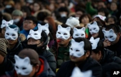 FILE - South Korean protesters wearing half masks attend an anti-government rally in downtown Seoul, South Korea, Dec. 19, 2015.