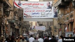 People walk under posters of Egyptian President Abdel Fattah al-Sisi for the upcoming presidential election, in Cairo, March 19, 2018. 