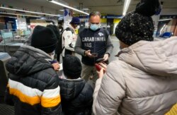 A Carabinieri policeman checks the green health pass of public transportation passengers in Rome, Italy, Dec. 6, 2021, on the first day a super green health pass went into effect.