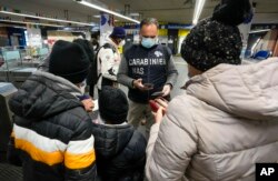 A Carabinieri policeman checks the green health pass of public transportation passengers in Rome, Italy, Dec. 6, 2021, on the first day a super green health pass went into effect.