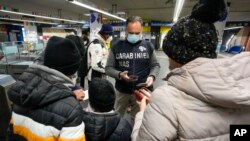 A Carabinieri policeman checks the green health pass of public transportation passengers in Rome, Italy, Dec. 6, 2021, on the first day a super green health pass went into effect. 