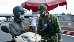 An army soldier checks identifications at a COVID-19 lockdown checkpoint in Ho Chi Minh City, Vietnam, Monday, Aug. 23, 2021. (Vu Tien Luc/VNA via AP)