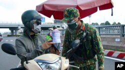 An army soldier checks identifications at a COVID-19 lockdown checkpoint in Ho Chi Minh City, Vietnam, Monday, Aug. 23, 2021. (Vu Tien Luc/VNA via AP)