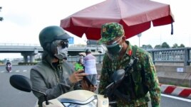 An army soldier checks identifications at a COVID-19 lockdown checkpoint in Ho Chi Minh City, Vietnam, Monday, Aug. 23, 2021. (Vu Tien Luc/VNA via AP)
