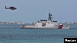 Un helicóptero vuela cerca de un barco de la Guardia Costera estadounidense en el Puerto de San Juan, Puerto Rico.