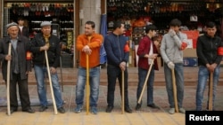 Shopkeepers line up with wooden clubs to perform their daily anti-terror drill outside the bazaar in Kashgar, Xinjiang Uighur Autonomous Region, China, March 24, 2017.