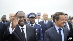 Le président Alassane Ouattara (à g.) en compagnie de son homologue français Nicolas Sarkozy, samedi à l'aéroport de Yamoussoukro.