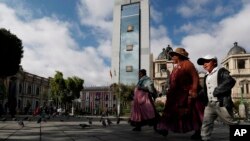 Bolivianos caminan en la Plaza Murillo, frente al palacio presidencial, el viejo palacio presidencial y el Congreso nacional en el centro de La Paz, en el distrito histórico. Oct. 16, 2019. AP/Juan Carita.