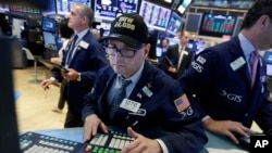 FILE - A trader wears a "Dow 22,000" hat as he works at his post on the floor of the New York Stock Exchange, Wednesday, Aug. 2, 2017. 