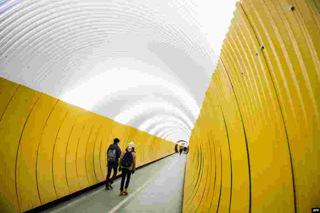 People walk in the Brunkeberg Tunnel, a 231-meter-long passageway for pedestrians, in Norrmalm, Stockholm, Sweden.