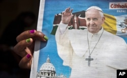 FILE - A churchgoer holds a copy of the Catholic Mirror newspaper showing a photograph of Pope Francis, after mass outside the Holy Family Minor Basilica in downtown Nairobi, Kenya, Nov. 22, 2015.