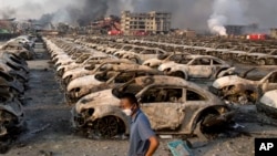 A man walks past wreckage from the Tianjin warehouse explosion.