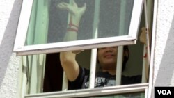 Tep Vanny waves her hand from a window at Phnom Penh Municipal Court as she is being questioned by the court over the Black Monday campaign, Phnom Penh, Cambodia, Wednesday, August 17, 2016. ( Leng Len/VOA Khmer) ​​​​