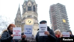 Waga Berlin dan para pengungsi berkumpul bersama menyanyikan lagu "We Are The World" di depan Kaiser Wilhelm Gedaechtniskirche (Gereja untuk memperingati Kaiser Wilhelm) di Berlin, Jerman, 21 Desember 2016, pasca insiden pasar Natal yang mengguncang kota itu Senin malam.