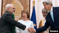 U.S. Secretary of State John Kerry, right, and Iranian Foreign Minister Javad Zarif, left, shake hands as Omani Foreign Minister Yussef bin Alawi, second from right, and EU envoy Catherine Ashton watch in Muscat, Oman, Nov. 9, 2014. 