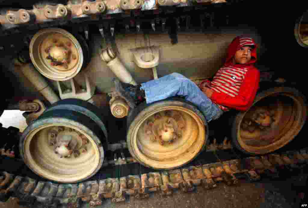 A boy sits inside the tracks of an army tank in Tahrir Square, Cairo on Friday. (Reuters/Suhaib Salem)