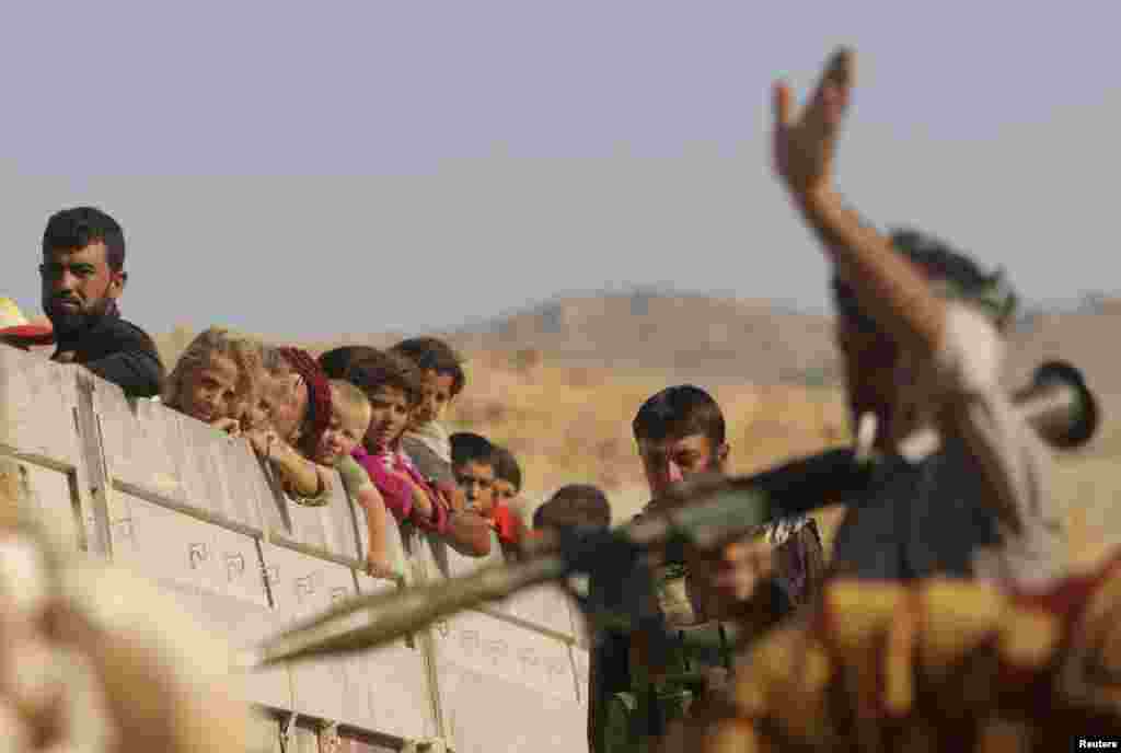 A Yazidi fighter who recently joined the Kurdish People's Protection Units (YPG) gestures while securing a road in Mount Sinjar in northern Iraq for displaced people from the Yazidi religious minority fleeing violence from forces loyal to the Islamic Stat