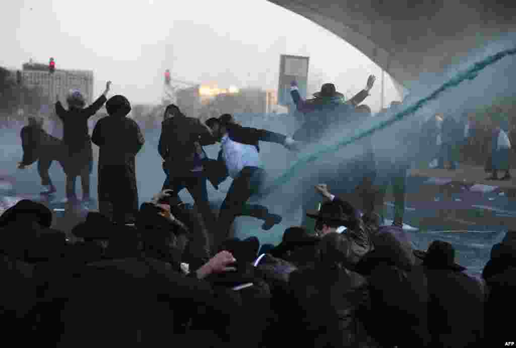 Members of the Israeli security forces use a foul-smelling spray known as &quot;skunk&quot; as they try to remove ultra-Orthodox Jews from blocking the road in a demonstration against Israeli army conscription in Jerusalem.