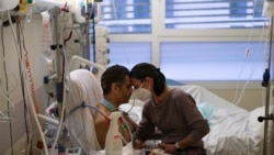 Amelie and Ludo Khayat hold each other during a visit at the COVID-19 intensive care unit of the la Timone hospital in Marseille, southern France, Thursday, Dec. 23, 2021.