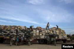 FILE - Workers illegally distribute old computers and printers to others for future recycling outside the government designated recycling center, at the township of Guiyu in China's southern Guangdong province, June 8, 2015.