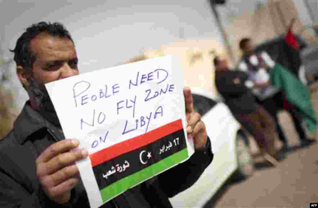 A Libyan man holds up a sign asking for a no-fly zone over Libya near the border town of Musa'id, Libya, Sunday, March 13, 2011. Moammar Gadhafi's forces swept rebels from one of their final strongholds on Libya's main coastal highway on Sunday, closing 