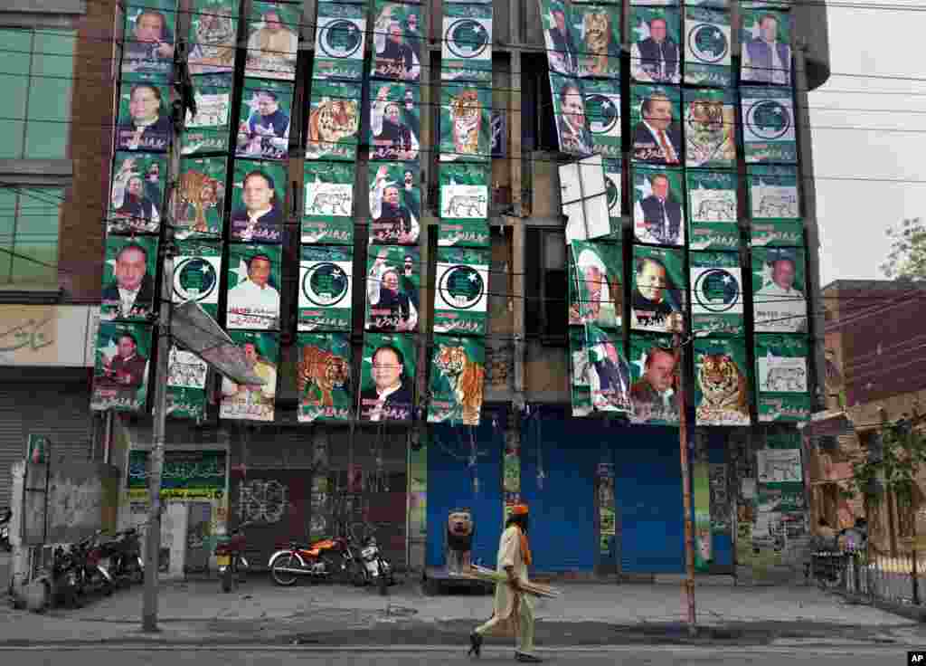 A man walks past posters of former prime minister and Pakistan Muslim League party chief Nawaz Sharif, displayed on his party&#39;s office building in Lahore, May 12, 2013.