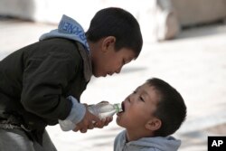 Migrant children share water as they pass time in Victoria square in central Athens, where many migrants stay temporarily before trying to continue their trip to more prosperous northern European countries, Sept. 22, 2015.