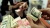 Seorang pegawai valas menghitung uang kertas dolar AS dan Rupiah (foto: ilustrasi). Kurs dolar AS terus menguat dan telah menembus Rp 16.300 per 1 dolar AS. 