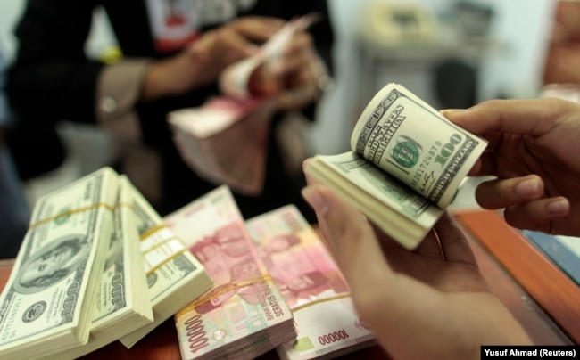 Seorang pegawai valas menghitung uang kertas dollar AS dan rupiah, di Makassar, Sulawesi Selatan, 31 Januari 2013. (Foto: Yusuf Ahmad/Reuters)