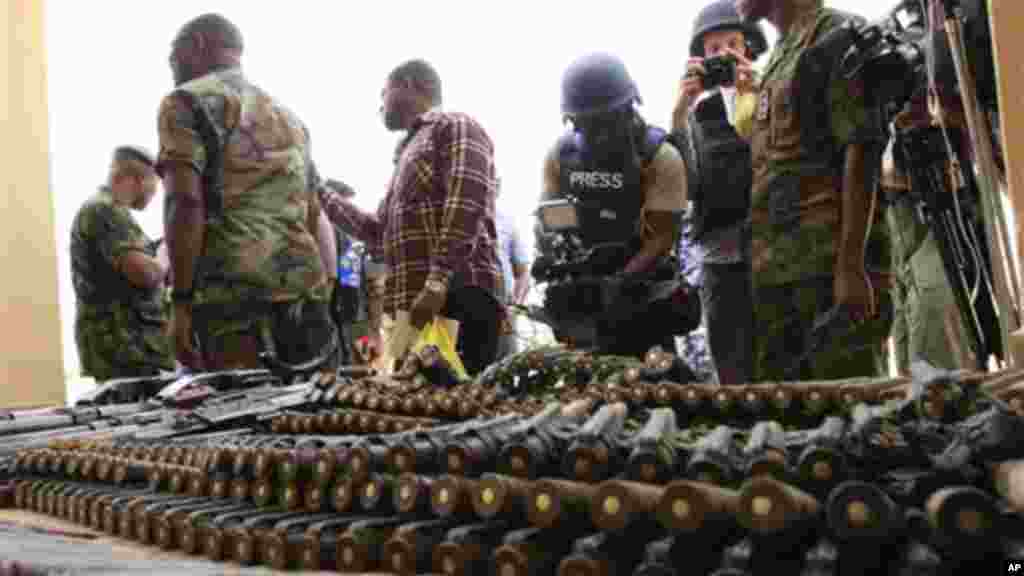 Journalists look at arms and ammunition which military commanders say they previously seized from Islamic fighters in Maiduguri, Nigeria.