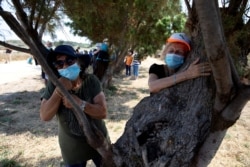 People take part in a campaign by Israel's Nature and Parks Authority calling on Israelis to join sightseeing tours and find comfort in tree hugging amid a spike in the coronavirus disease in Apollonia National Park, near Herzliya, Israel July 7, 2020. (Reuters)