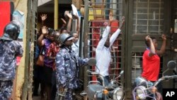 Residents are ordered out of a building with their hands in the air as security forces pursue protesters in Kampala, Uganda, Aug. 20, 2018. 