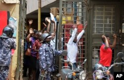 FILE - Residents are ordered out of a building with their hands in the air as security forces pursue protesters in Kampala, Uganda, Aug. 20, 2018.