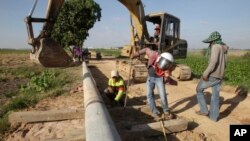 FILE PHOTO - Cambodian workers prepare an electricity pole for placing at Samroang Tiev village at the outskirt of Phnom Penh, Cambodia, Thursday, Dec. 7, 2017. (AP Photo/Heng Sinith)