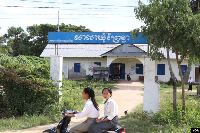 Students drive past the Prey Khla commune office in Takeo province, Nov. 27, 2017.