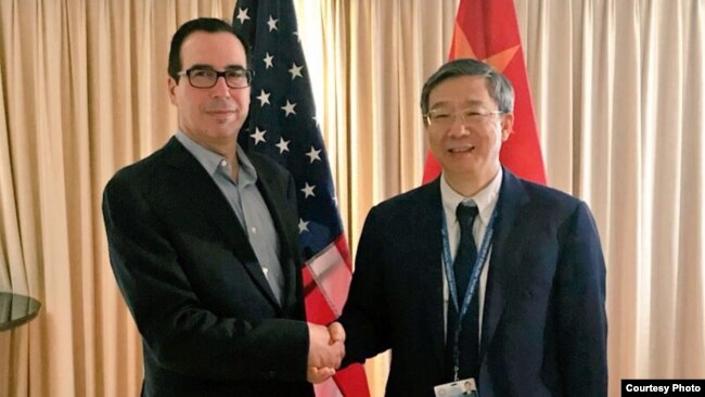 2018年10月10日，美国财政部长姆努钦和中国人民银行行长易刚在国际会议期间握手，姆努钦说双方讨论了重要经济问题（姆努钦推特图片）。