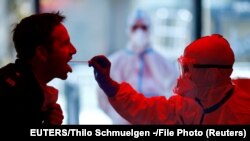 Seorang petugas medis melakukan tes swab Covid-19 terhadap para petugas layanan publik di Cologne, Jerman. 