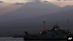 Sebuah kapal feri melintasi Selat Bali membawa warga ke pelabuhan Ketapang, Jawa Timur, dari Gilimanuk, sementara di latar belakang Gunung Raung mengeluarkan asap vulkaniknya (12/7).