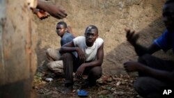 Men take cover in a toilet as heavy gunfire erupts in the Miskin district of Bangui, Central African Republic, Monday Feb. 3, 2014. In what a French soldier on the scene described as the heaviest exchange of fire he'd seen since early December 2013, Musli