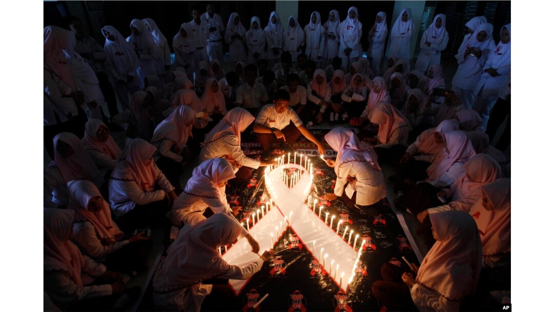 Mahasiswa kedokteran menyalakan lilin pada acara peringatan Hari AIDS Sedunia di Surabaya, Jawa Timur, Senin, 1 Desember 2015. (Foto: AP)