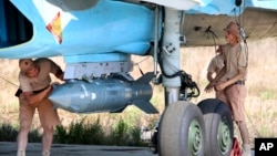 Russian military support crew attach a satellite guided bomb to SU-34 jet fighter at Hmeimim airbase in Syria, Oct. 3, 2015.