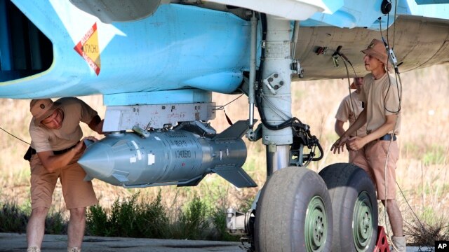 Equipo de apoyo militar ruso coloca una bomba guiada por satélite a un jet de combate Su-34 en la base aérea en Hmeimim en Siria. 