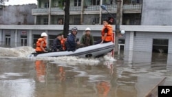 Sebuah perahu karet menyusuri kota Anju di propinsi Phyongan Utara, Korea Utara (30/7). Topan dan hujan di wilayah ini telah merendam bangunan dan areal persawahan di Korea Utara sejak pertengahan Juli lalu..