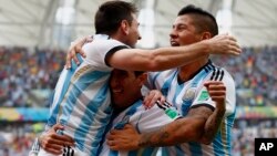 Argentina's Lionel Messi (L-R) celebrates with teammates Angel Di Maria and Marcos Rojo after scoring against Nigeria during their 2014 World Cup Group F soccer match at the Beira Rio stadium in Porto Alegre, June 25, 2014. 