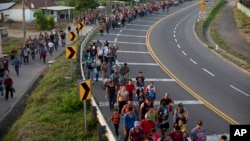 FILE - Central American migrants, part of a caravan hoping to reach the U.S. border, walk in Frontera Hidalgo, Mexico, April 12, 2019.