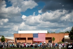 Members of the audience stand in front of a large American flag as Democratic presidential candidate Hillary Clinton, accompanied by Democratic vice presidential candidate, Sen. Tim Kaine, D-Va., speaks at at rally at Fort Hayes Metropolitan Education Center in Columbus, Ohio, July 31, 2016.