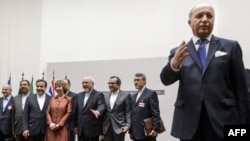 French Foreign Minister Laurent Fabius (R) gestures as EU foreign policy chief Catherine Ashton (4thL) pose with Iranian Foreign Minister Mohammad Javad Zarif (5thL) next to the Iranian delegation after a statement on Nov. 24, 2013 in Geneva. 