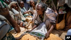 FILE - An Ethiopian woman argues with others over the allocation of yellow split peas distributed by the Relief Society of Tigray in the town of Agula, in the Tigray region of northern Ethiopia, May 8, 2021.